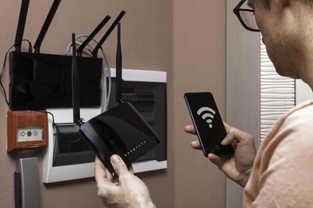 👉 person moving closer to WiFi router with smartphone to improve signal